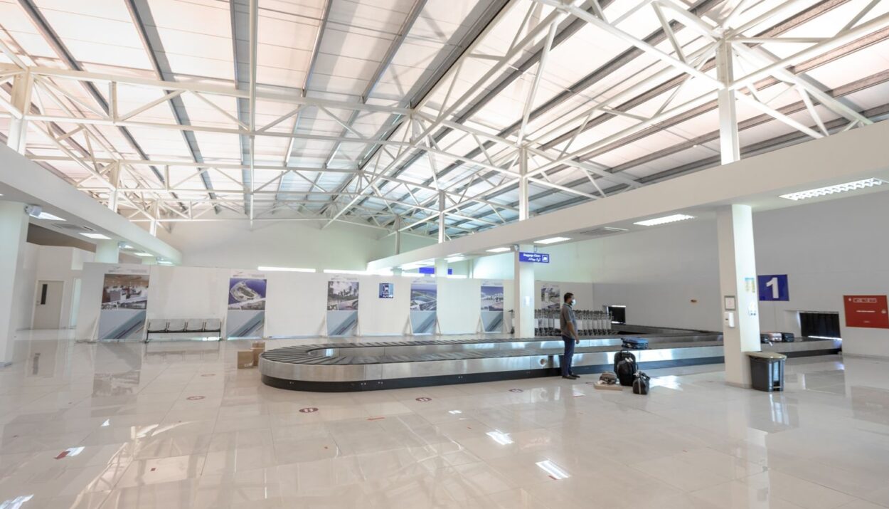 Zone de récupération des bagages dans un aéroport, voyageur attendant sa valise près du tapis
