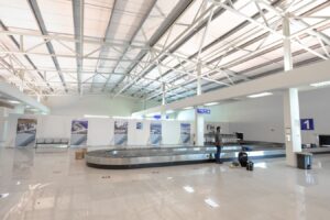 Zone de récupération des bagages dans un aéroport, voyageur attendant sa valise près du tapis