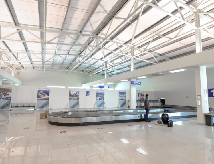 Zone de récupération des bagages dans un aéroport, voyageur attendant sa valise près du tapis
