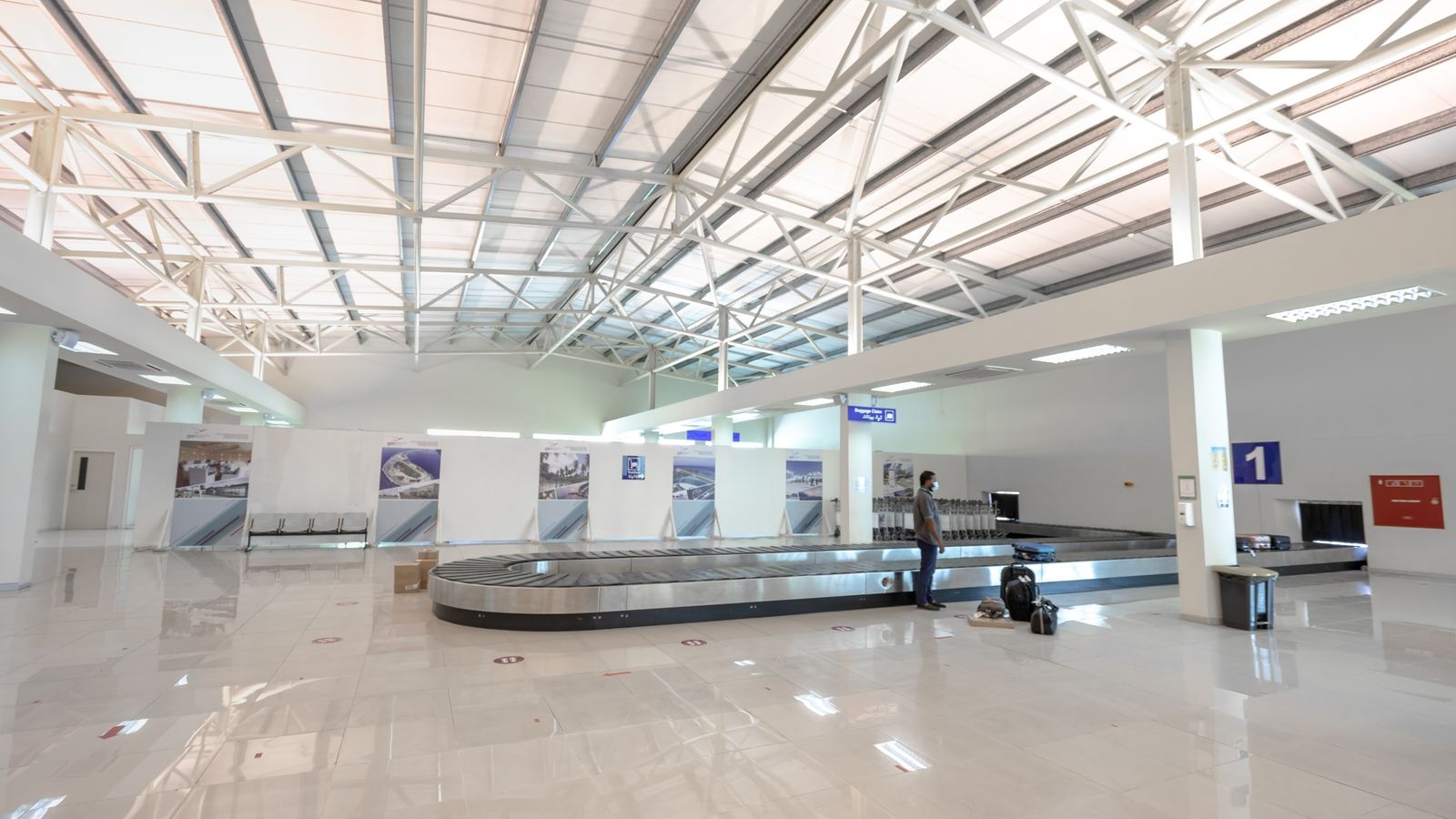 Zone de récupération des bagages dans un aéroport, voyageur attendant sa valise près du tapis