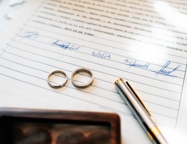 Alliances de mariage posées sur un contrat de mariage signé par les époux et un notaire