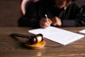Juge signant un document sur son bureau, symbole de la justice pour un dossier d'abus de confiance