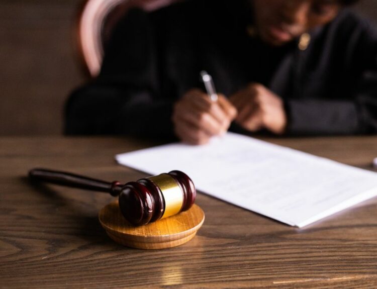 Juge signant un document sur son bureau, symbole de la justice pour un dossier d'abus de confiance